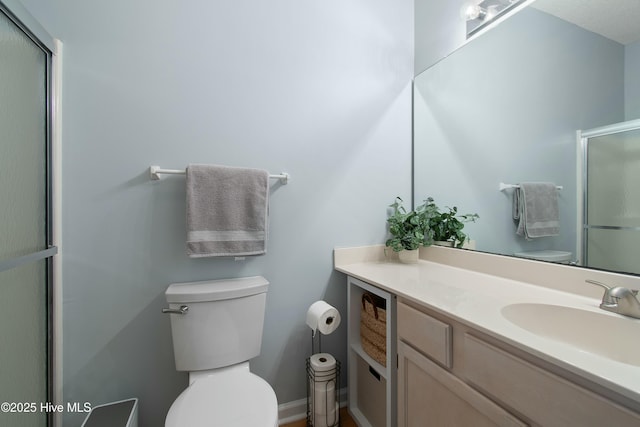 bathroom featuring vanity, toilet, and a shower with shower door