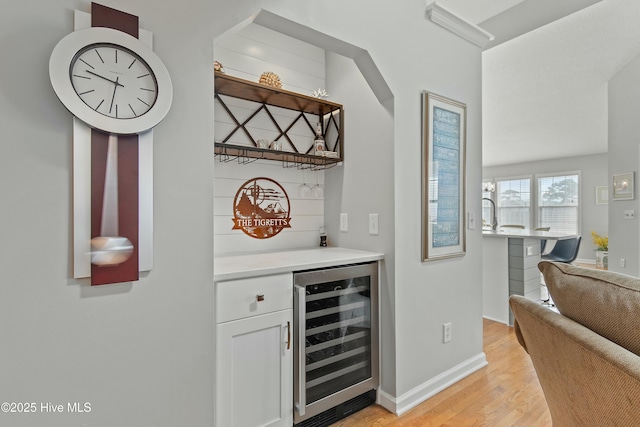 bar featuring beverage cooler, light wood-type flooring, and white cabinets