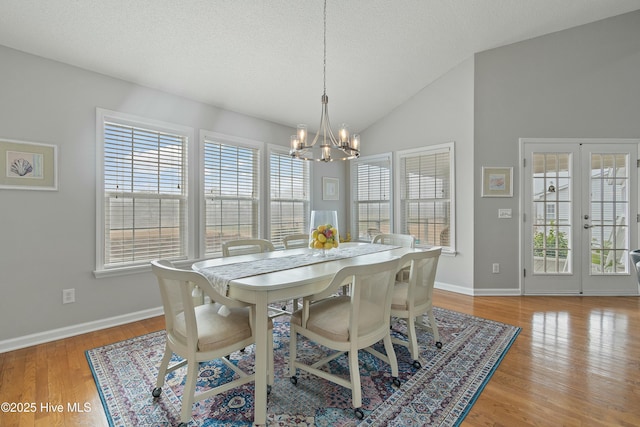 dining room with french doors, lofted ceiling, a textured ceiling, and light wood-type flooring