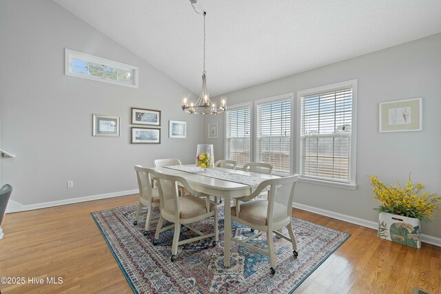 dining room featuring lofted ceiling, plenty of natural light, a notable chandelier, and light wood-type flooring