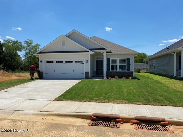 view of front of property featuring an attached garage, a front lawn, and concrete driveway
