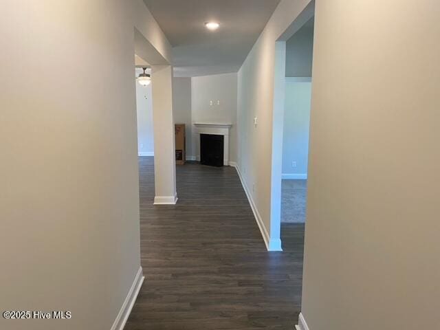 corridor featuring baseboards and dark wood-style flooring