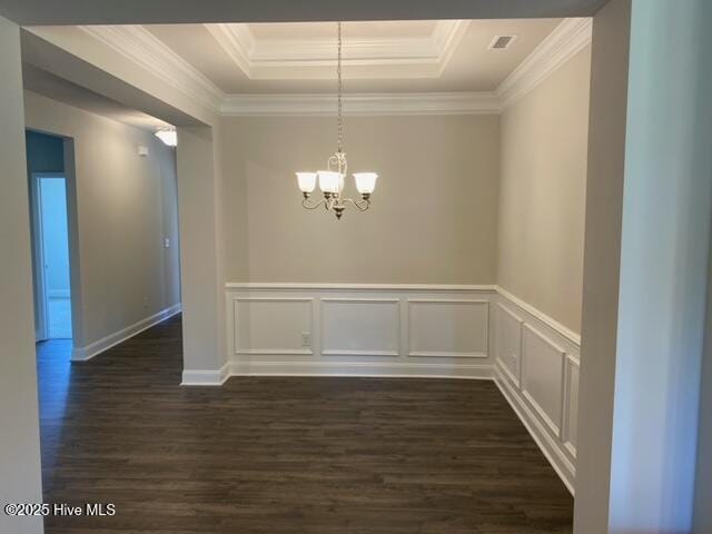 unfurnished dining area with a tray ceiling, dark wood finished floors, crown molding, and an inviting chandelier