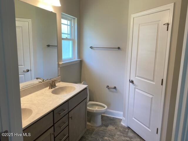 bathroom featuring a sink, double vanity, and toilet