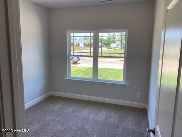 carpeted empty room featuring baseboards and visible vents