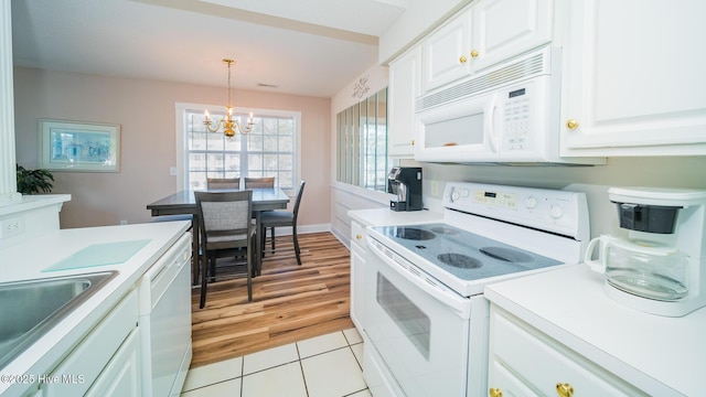 kitchen with light tile patterned flooring, a notable chandelier, pendant lighting, white appliances, and white cabinets