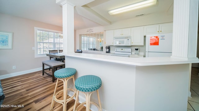 kitchen featuring a chandelier, a breakfast bar area, white appliances, and kitchen peninsula