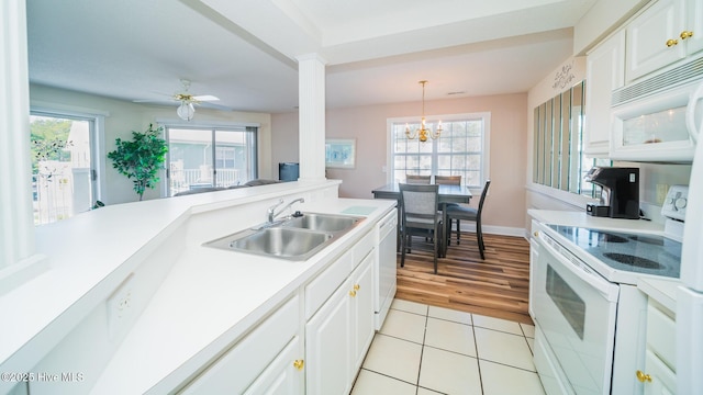 kitchen featuring sink, white appliances, white cabinets, light tile patterned flooring, and decorative light fixtures