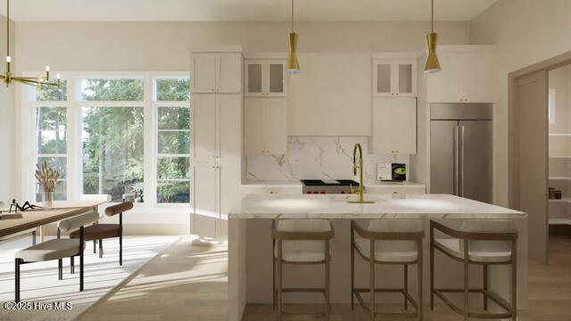 kitchen with tasteful backsplash, stainless steel built in refrigerator, decorative light fixtures, and white cabinets