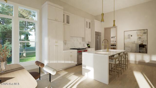 kitchen with pendant lighting, white cabinetry, a kitchen breakfast bar, high quality appliances, and a center island with sink