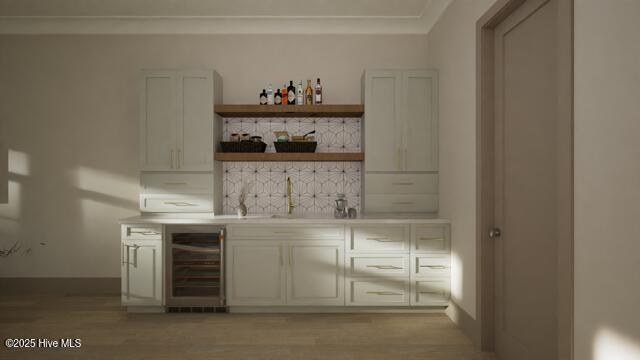 bar featuring sink, ornamental molding, light hardwood / wood-style floors, and beverage cooler