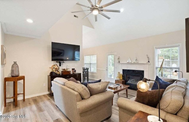 living room featuring a high end fireplace, high vaulted ceiling, and light wood-type flooring