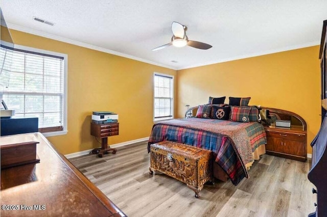 bedroom with ceiling fan, ornamental molding, and light hardwood / wood-style floors