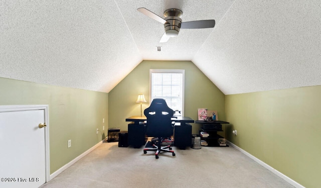 office space featuring ceiling fan, vaulted ceiling, light carpet, and a textured ceiling