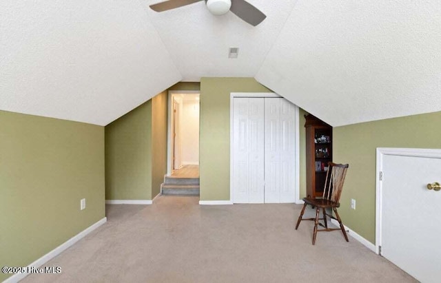 bonus room with light carpet, ceiling fan, vaulted ceiling, and a textured ceiling