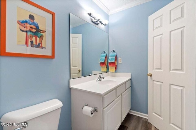 bathroom with ornamental molding, toilet, hardwood / wood-style floors, and vanity