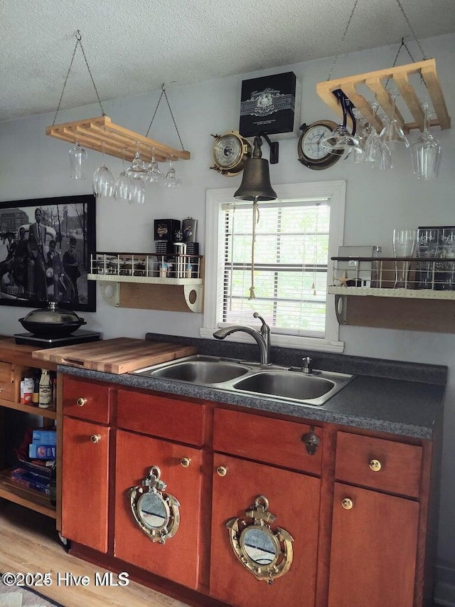 kitchen featuring sink, light hardwood / wood-style flooring, and a textured ceiling