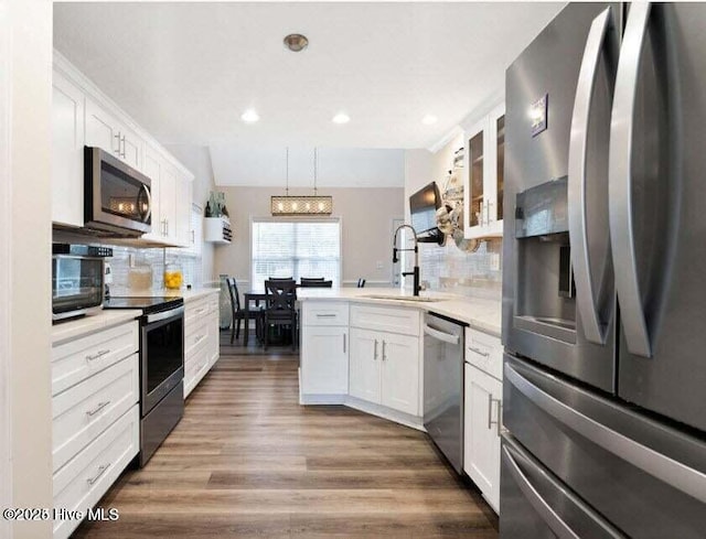 kitchen featuring dark wood-type flooring, sink, white cabinetry, decorative light fixtures, and appliances with stainless steel finishes