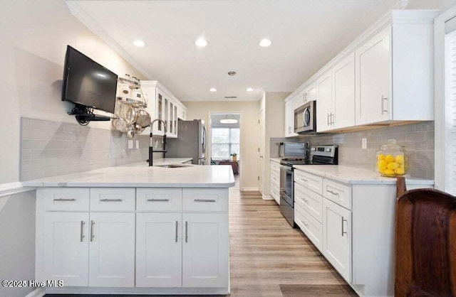 kitchen featuring sink, light stone counters, stainless steel appliances, light hardwood / wood-style floors, and white cabinets