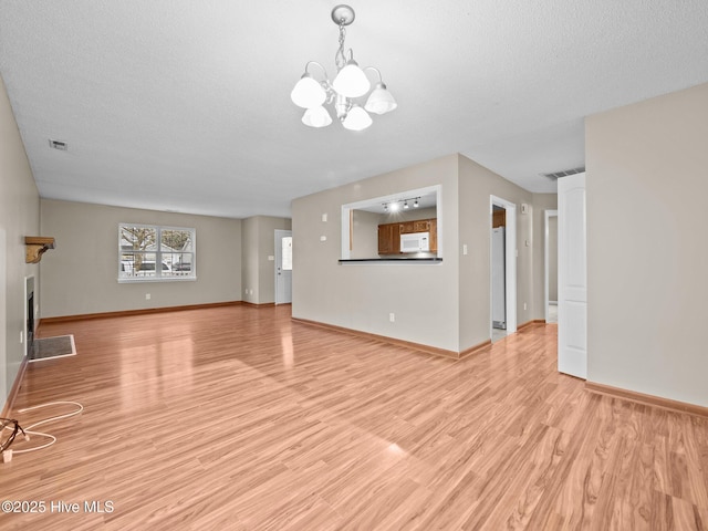 unfurnished living room featuring light hardwood / wood-style flooring, a chandelier, and a textured ceiling