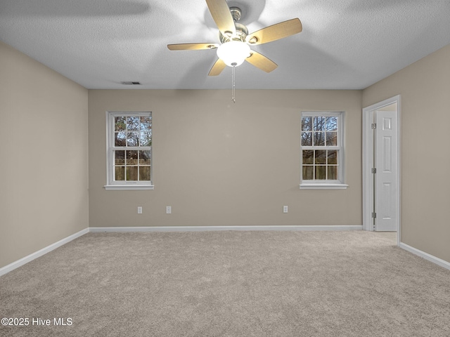 empty room featuring ceiling fan, light carpet, and a textured ceiling