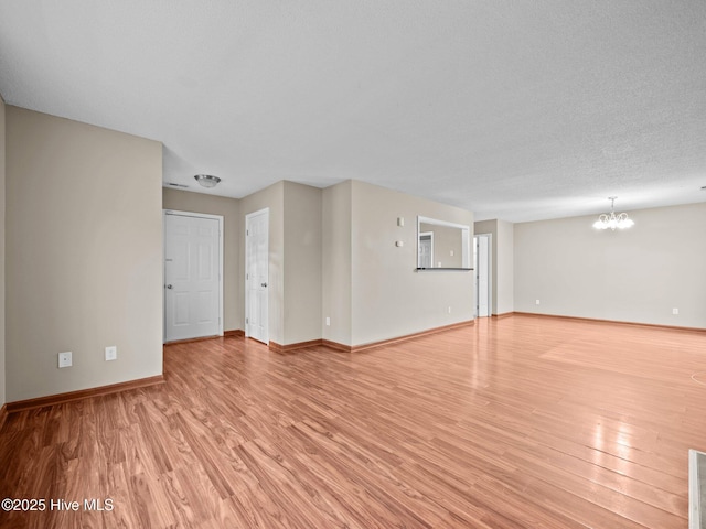 unfurnished living room with a chandelier, a textured ceiling, and light wood-type flooring