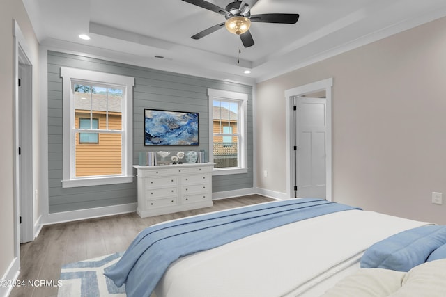 bedroom featuring wooden walls, wood finished floors, baseboards, recessed lighting, and a raised ceiling