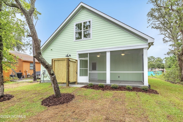 back of property featuring a ceiling fan, a yard, and a sunroom