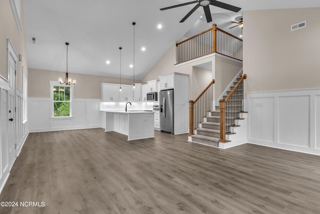 unfurnished living room featuring visible vents, ceiling fan with notable chandelier, stairway, and wood finished floors