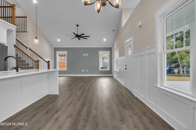 unfurnished living room featuring dark wood finished floors, stairway, a decorative wall, and plenty of natural light