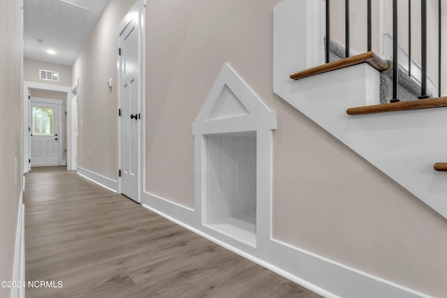 hall with wood finished floors, visible vents, and baseboards