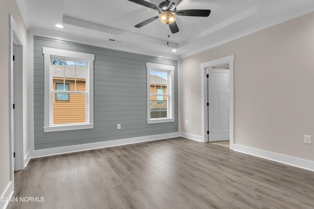 empty room with baseboards, a healthy amount of sunlight, wood finished floors, and a ceiling fan