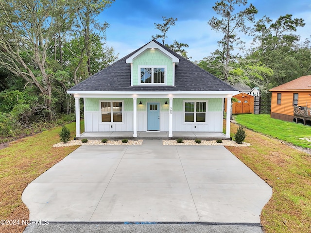 view of front of home featuring a porch, board and batten siding, a shingled roof, and a front lawn