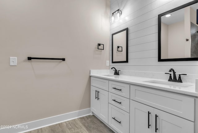 bathroom with double vanity, baseboards, and a sink