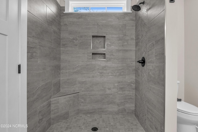 full bathroom featuring a tile shower and toilet