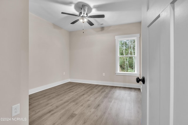 spare room featuring baseboards, wood finished floors, and a ceiling fan