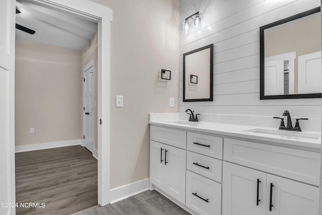 bathroom featuring double vanity, wood finished floors, baseboards, and a sink