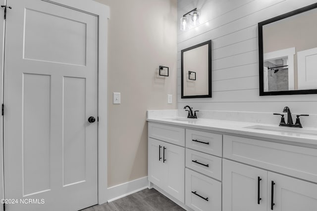 bathroom with baseboards, wood finished floors, double vanity, and a sink
