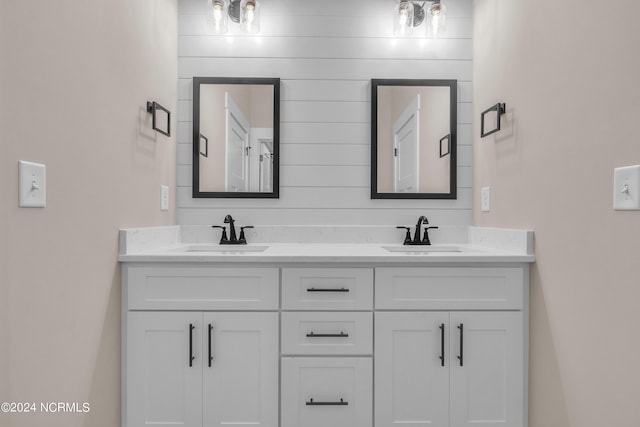 bathroom featuring baseboards, double vanity, and a sink