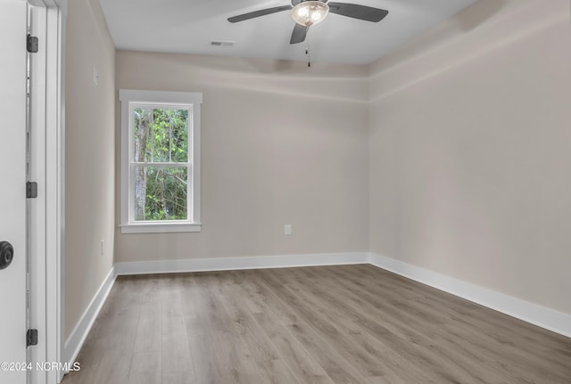 spare room with baseboards, visible vents, a ceiling fan, and wood finished floors