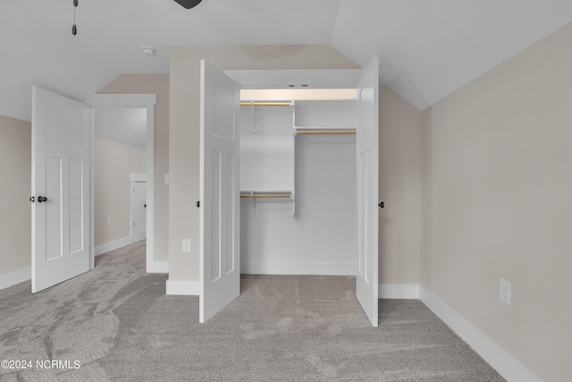 unfurnished bedroom featuring baseboards, lofted ceiling, carpet flooring, and a ceiling fan