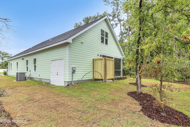 rear view of property featuring a shingled roof, central AC unit, and a lawn