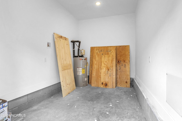 unfurnished room featuring water heater and concrete floors