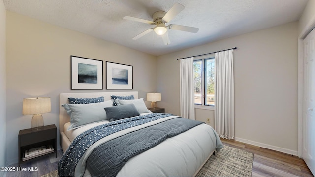 bedroom featuring ceiling fan, a textured ceiling, and light hardwood / wood-style floors