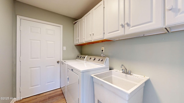 washroom featuring hardwood / wood-style flooring, cabinets, separate washer and dryer, and sink