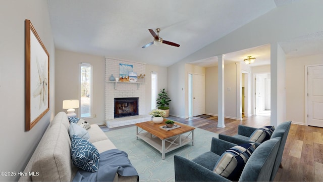 living room with lofted ceiling, a brick fireplace, hardwood / wood-style flooring, and ceiling fan