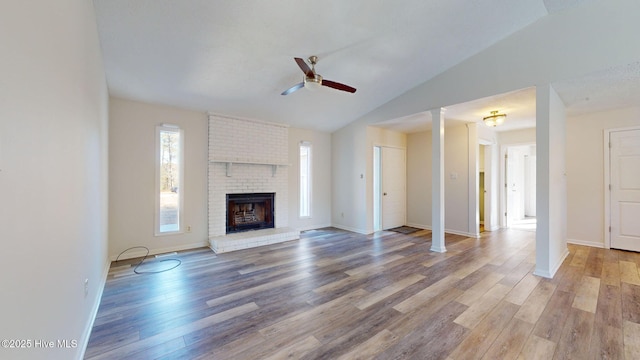 unfurnished living room with hardwood / wood-style flooring, lofted ceiling, a fireplace, and ceiling fan