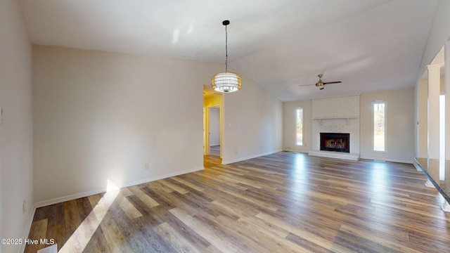 unfurnished living room with hardwood / wood-style flooring, a brick fireplace, lofted ceiling, and ceiling fan