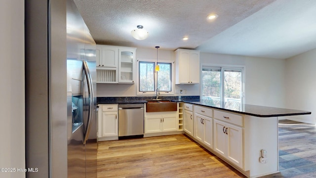 kitchen featuring white cabinetry, appliances with stainless steel finishes, decorative light fixtures, and kitchen peninsula