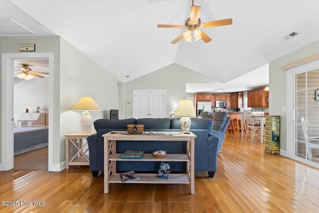 living room featuring ceiling fan, vaulted ceiling, and light hardwood / wood-style flooring